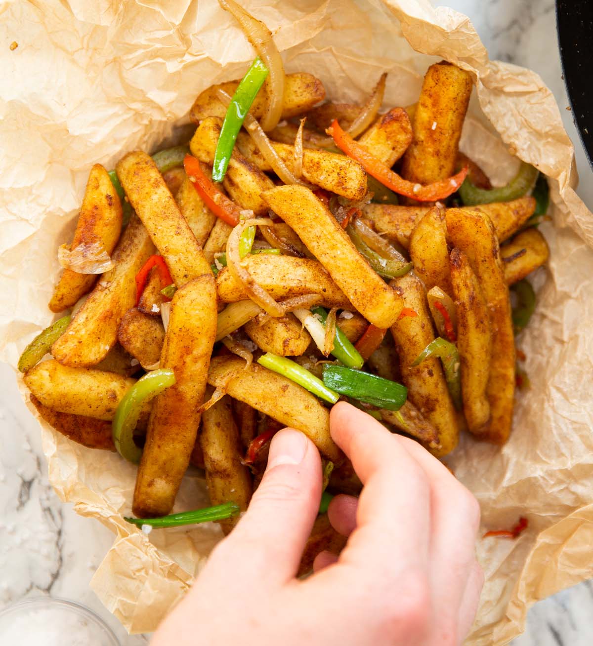 overhead shot of hand grabbing salt and chilli chips